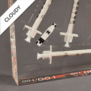 Plastic syringes that have bleed into the clear acrylic showing acrylic embedment failure.